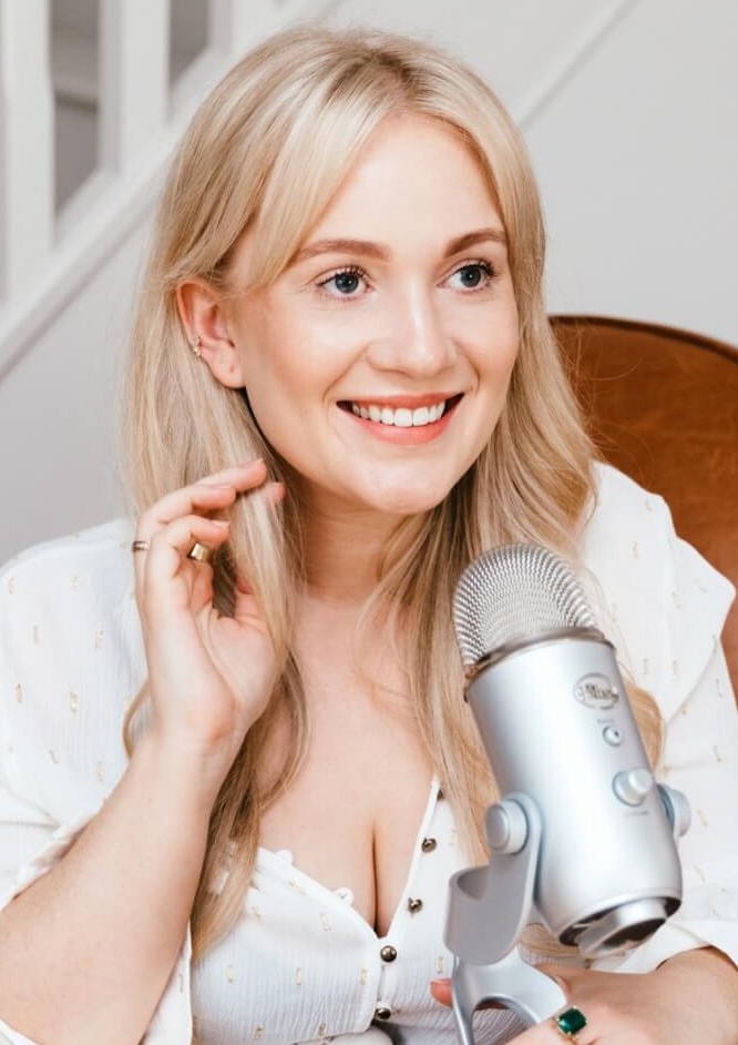 Millie Poppins smiling with a podcast microphone